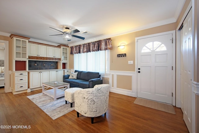 living room with light wood-type flooring, ceiling fan, and ornamental molding