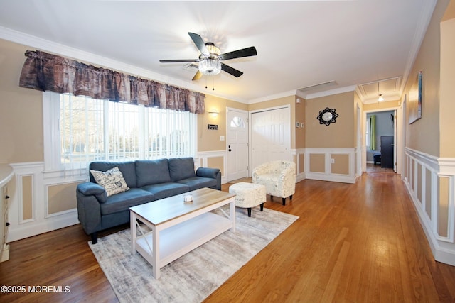 living room featuring hardwood / wood-style flooring, ceiling fan, and crown molding