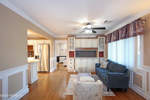 living room featuring ceiling fan, ornamental molding, light hardwood / wood-style flooring, and sink