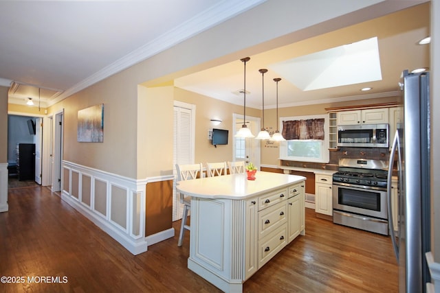 kitchen featuring a center island, decorative light fixtures, stainless steel appliances, a breakfast bar, and crown molding