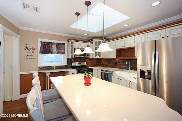 kitchen with decorative light fixtures, a skylight, ornamental molding, and appliances with stainless steel finishes