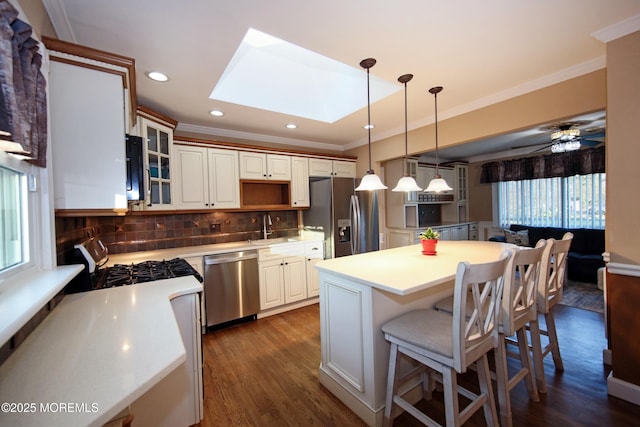 kitchen featuring ceiling fan, decorative backsplash, a skylight, pendant lighting, and appliances with stainless steel finishes