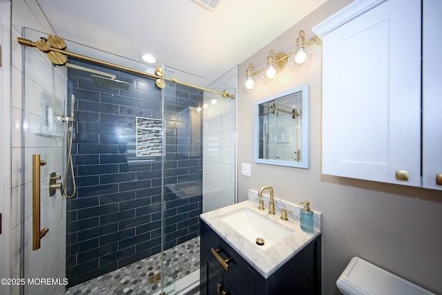 bathroom with toilet, vanity, and a shower with shower door