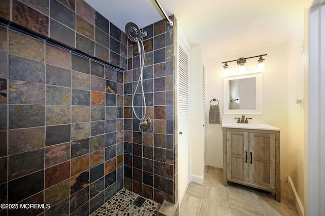 bathroom with a tile shower and vanity