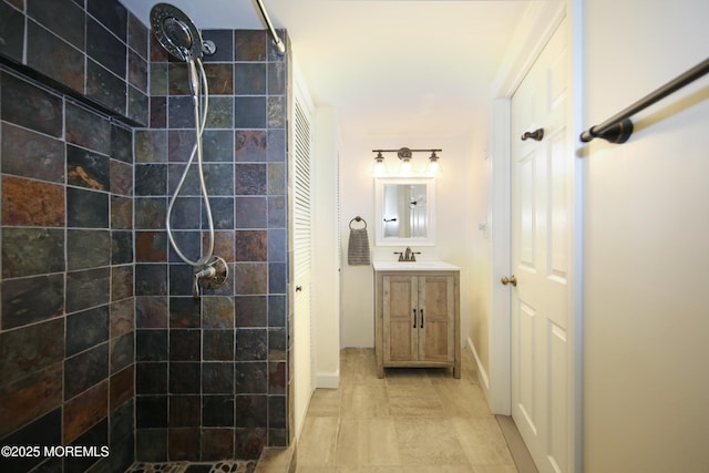 bathroom with a tile shower and vanity