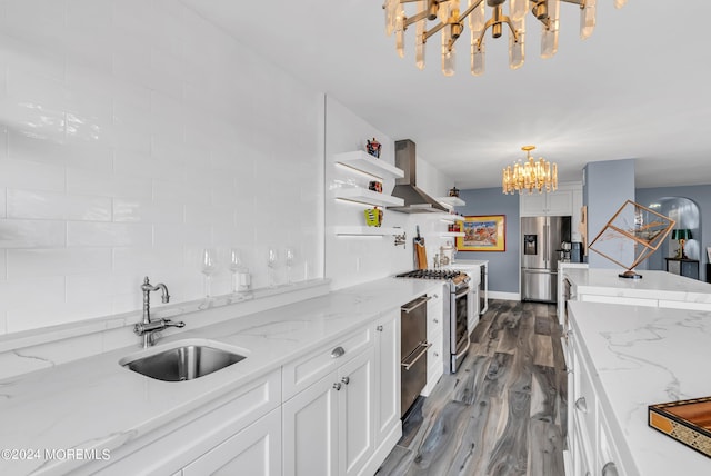 kitchen with sink, light stone counters, range hood, stainless steel appliances, and white cabinets