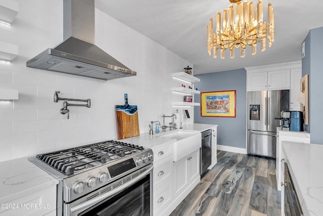 kitchen featuring decorative backsplash, stainless steel appliances, wall chimney exhaust hood, and white cabinets