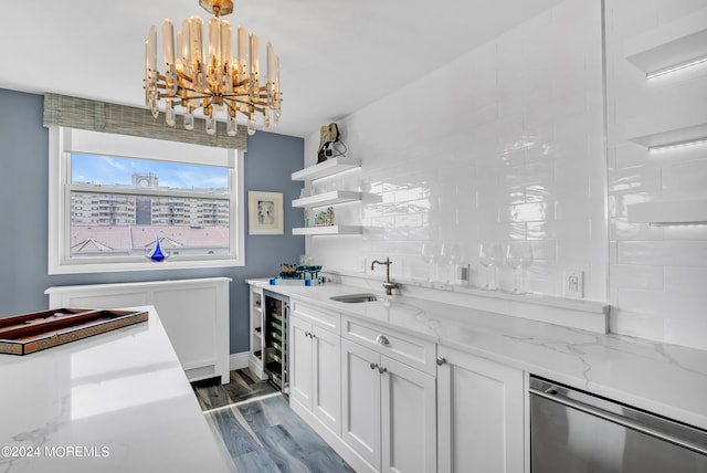 kitchen featuring sink, beverage cooler, light stone counters, white cabinetry, and decorative light fixtures