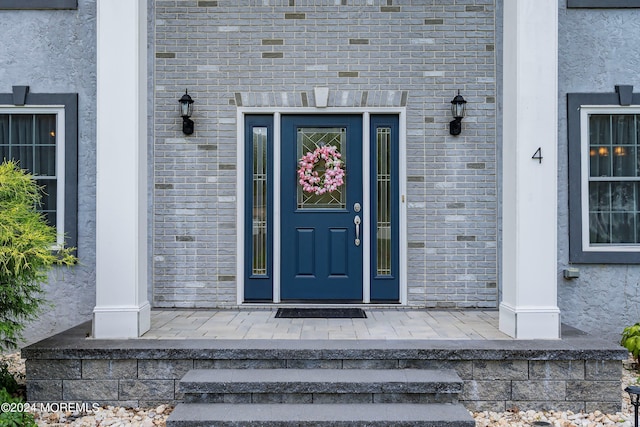 doorway to property with brick siding and stucco siding