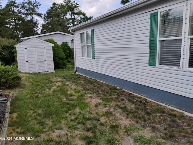 view of home's exterior with a storage unit, a lawn, and an outdoor structure