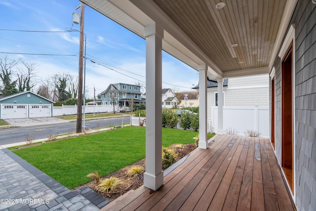 wooden deck with a garage, a porch, an outbuilding, and a yard