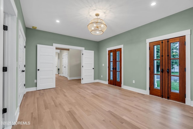 interior space with light wood-type flooring, french doors, and a chandelier