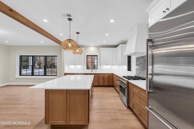 kitchen featuring premium range hood, a spacious island, pendant lighting, high quality appliances, and white cabinets