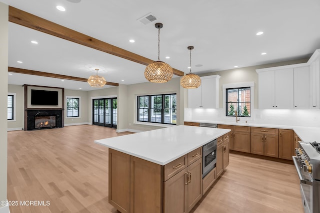 kitchen featuring decorative light fixtures, a kitchen island, a premium fireplace, appliances with stainless steel finishes, and white cabinets