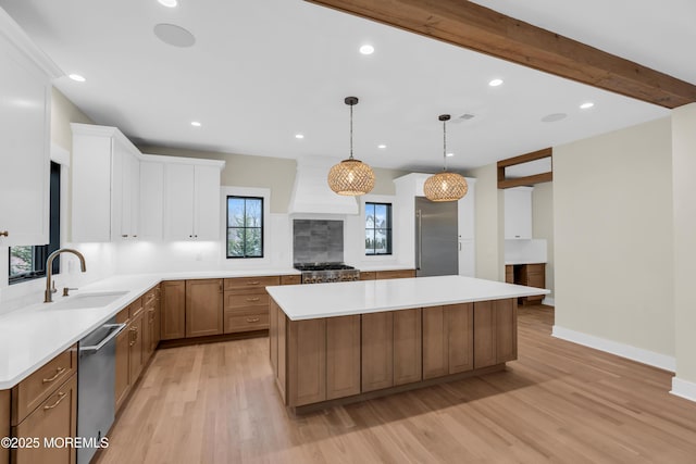 kitchen with decorative light fixtures, stainless steel appliances, beamed ceiling, sink, and a large island