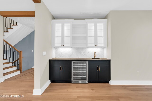 bar featuring wine cooler, backsplash, sink, light hardwood / wood-style flooring, and white cabinets