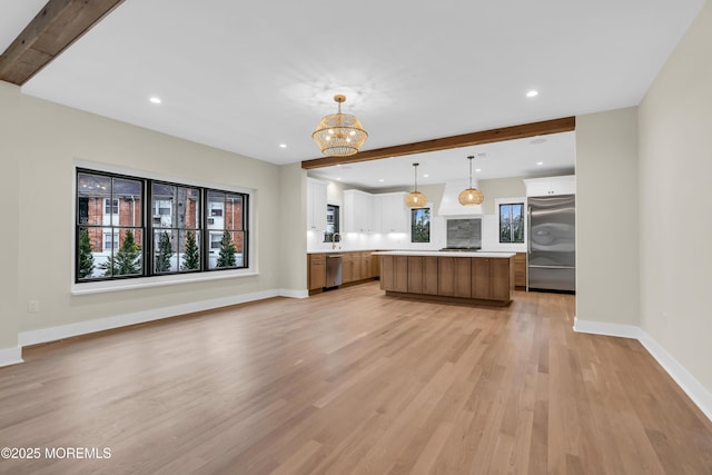 kitchen with light hardwood / wood-style floors, appliances with stainless steel finishes, a notable chandelier, hanging light fixtures, and a kitchen island