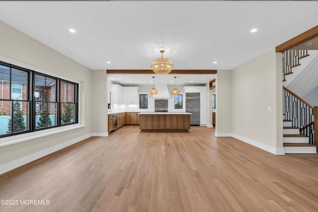 kitchen with a notable chandelier, light hardwood / wood-style floors, a center island, hanging light fixtures, and stainless steel appliances