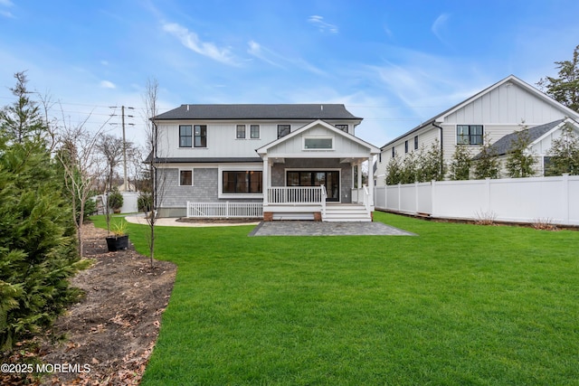 rear view of property featuring a yard, a patio area, and a porch