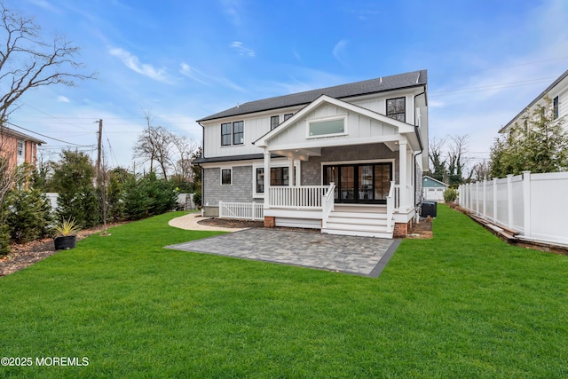 back of house featuring covered porch, a lawn, and a patio