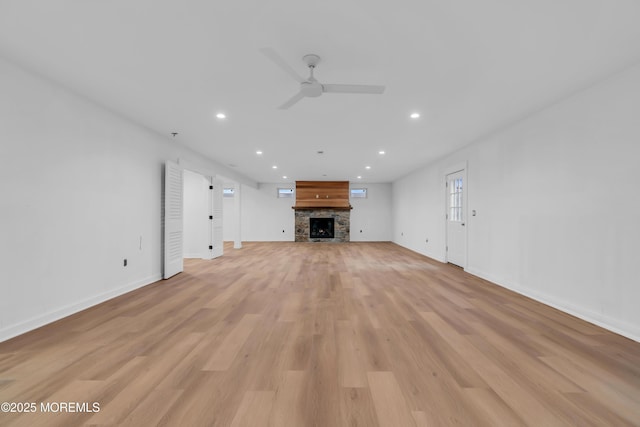 unfurnished living room featuring ceiling fan, light wood-type flooring, and a fireplace