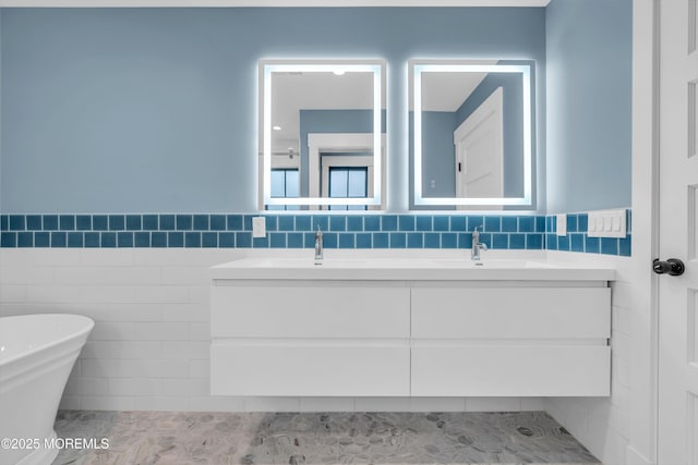 bathroom featuring a tub, tile walls, and vanity