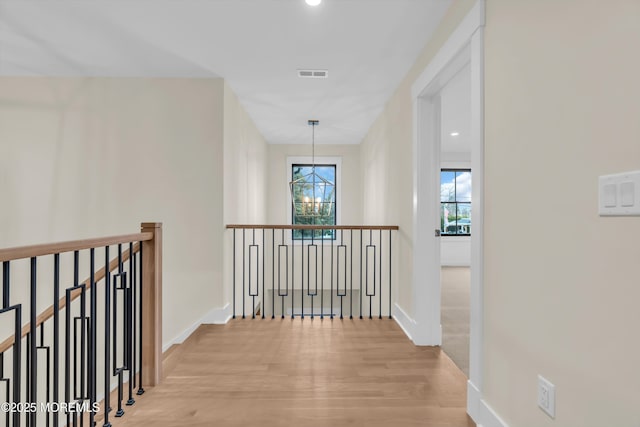 hall with light hardwood / wood-style floors and an inviting chandelier