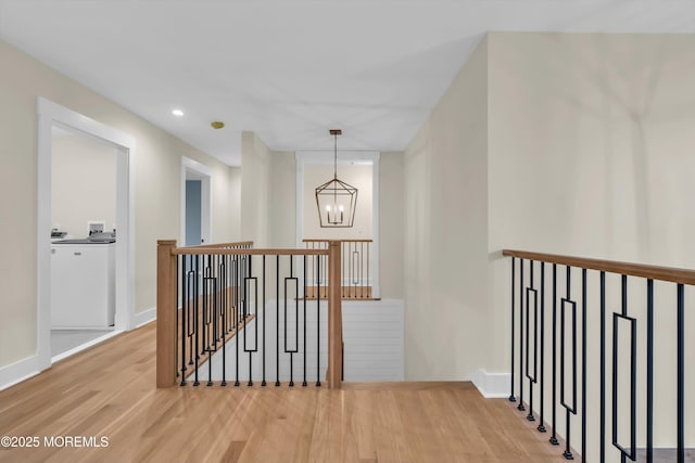 corridor featuring hardwood / wood-style floors, a notable chandelier, and washer / clothes dryer