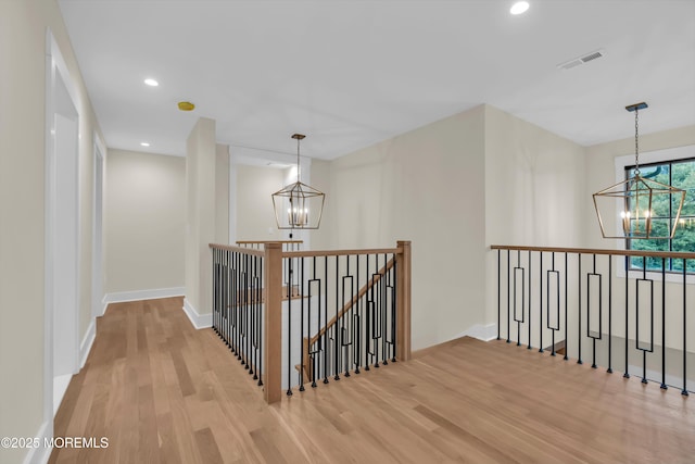 hallway with an inviting chandelier and light hardwood / wood-style floors