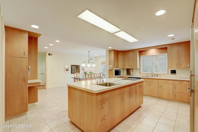 kitchen with light brown cabinets, a kitchen island with sink, a sink, light countertops, and hanging light fixtures