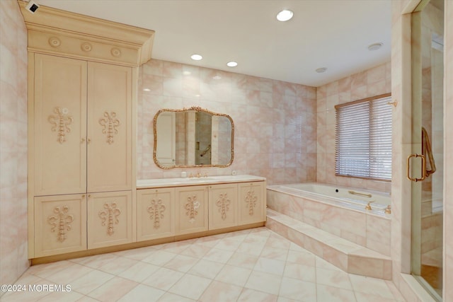 bathroom with tile walls, tile patterned floors, vanity, a bath, and recessed lighting