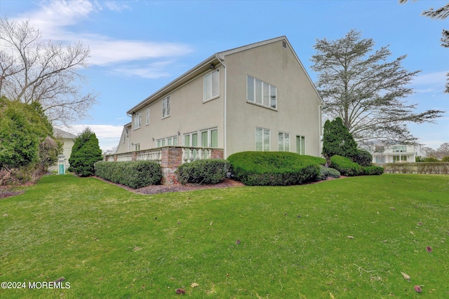 view of home's exterior featuring brick siding, a lawn, and stucco siding