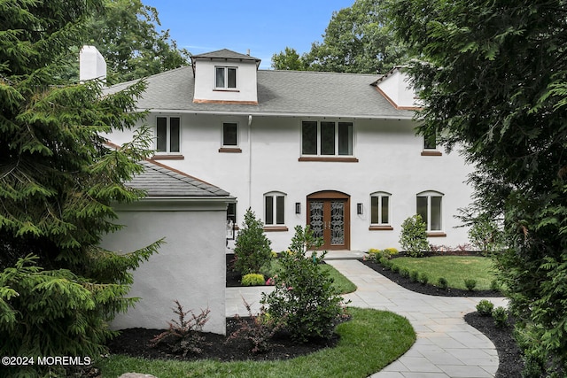 view of front of house featuring a chimney, roof with shingles, french doors, a front yard, and stucco siding