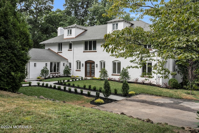 view of front facade with roof with shingles and a front lawn