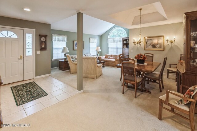 tiled dining room featuring an inviting chandelier and a tray ceiling