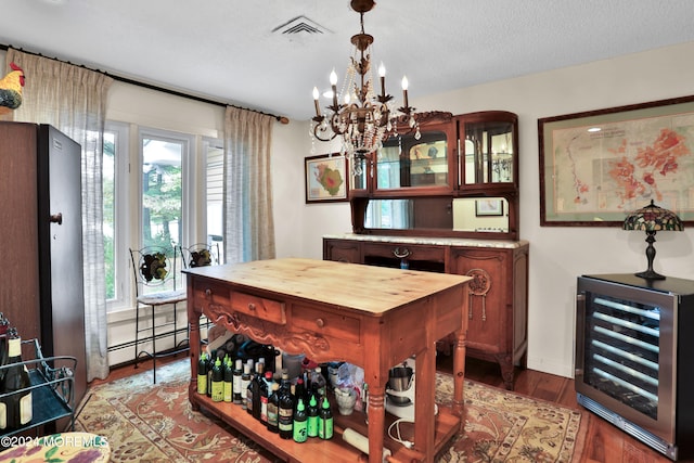 dining room featuring wood-type flooring, a textured ceiling, baseboard heating, beverage cooler, and a notable chandelier