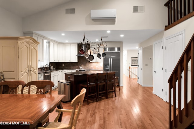 kitchen featuring a breakfast bar area, stainless steel appliances, backsplash, a center island, and light hardwood / wood-style floors