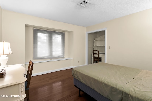 bedroom with a closet, a textured ceiling, and dark hardwood / wood-style flooring