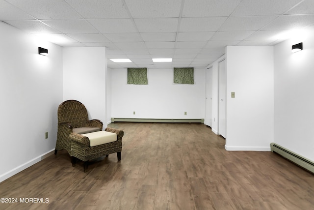 living area featuring a baseboard heating unit, a drop ceiling, and dark hardwood / wood-style floors