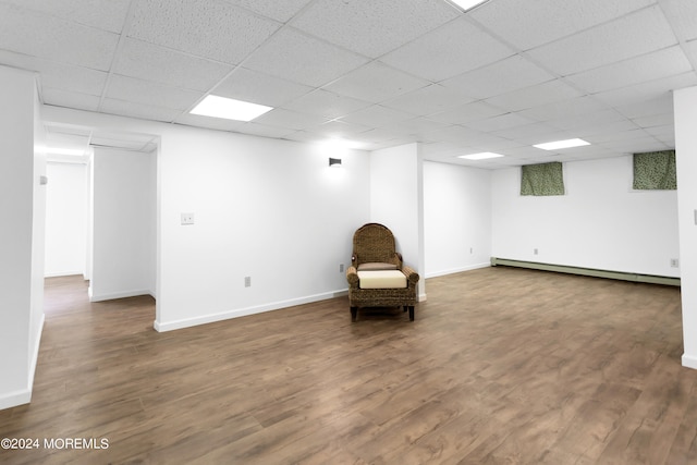 unfurnished room featuring a drop ceiling, hardwood / wood-style floors, and a baseboard radiator