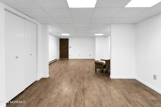 basement featuring a paneled ceiling, wood-type flooring, and a baseboard radiator