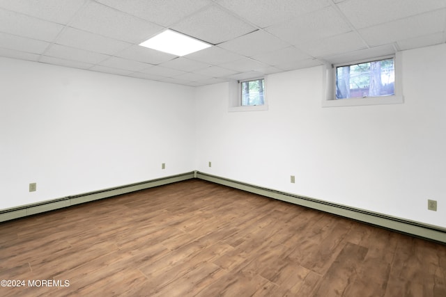 basement featuring a drop ceiling, wood-type flooring, and a healthy amount of sunlight