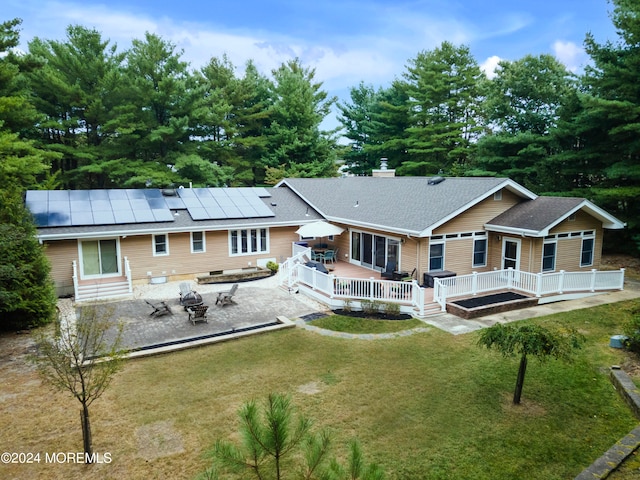 rear view of property featuring a patio area, solar panels, and a yard