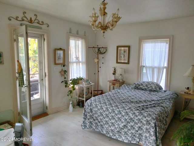 bedroom with an inviting chandelier, access to outside, and light hardwood / wood-style floors