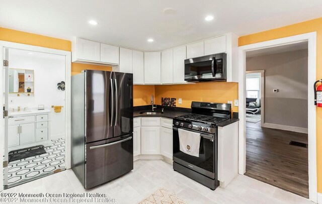 kitchen featuring stainless steel appliances, sink, light tile patterned floors, and white cabinetry