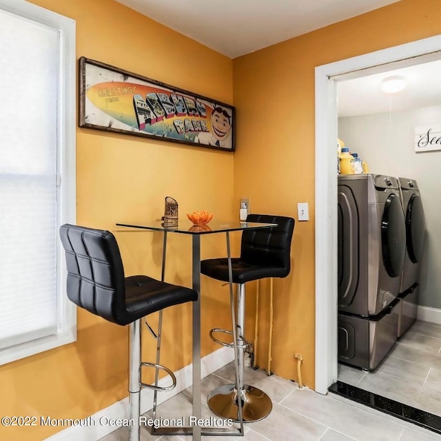 bar featuring washing machine and dryer and light tile patterned floors