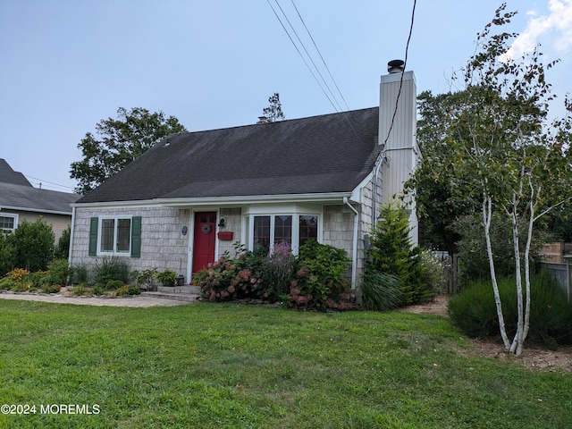 view of front of property with a front lawn, a chimney, and a shingled roof