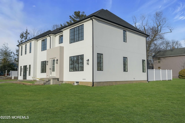 back of house featuring a lawn, fence, and stucco siding