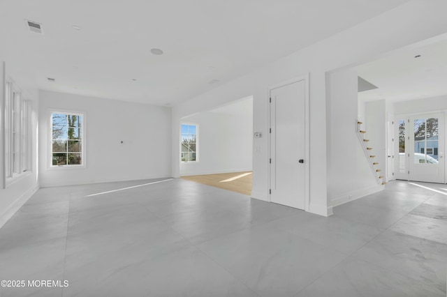 spare room with visible vents, stairway, and baseboards