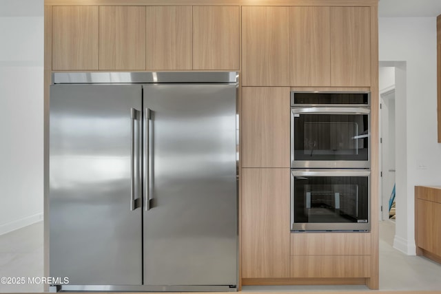 kitchen with light brown cabinets, appliances with stainless steel finishes, and modern cabinets